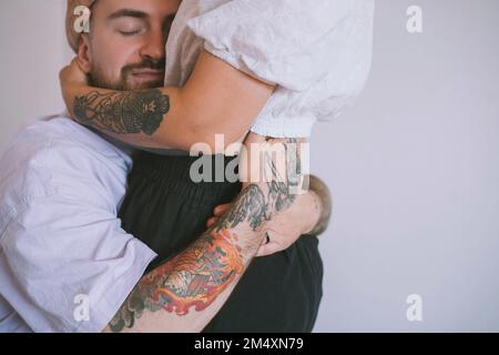 Hipster homme avec tatouage à la main embrassant la petite amie Banque D'Images