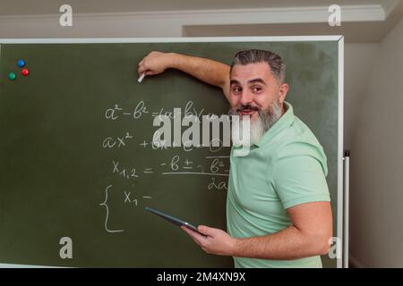 Professeur expliquant les mathématiques sur tableau noir avec tablette PC Banque D'Images