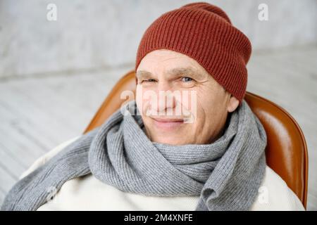Homme senior souriant portant un chapeau et une écharpe en tricot Banque D'Images