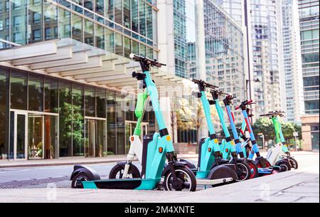 Trottinettes électriques garées devant les bâtiments Banque D'Images