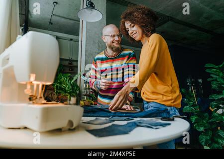 Des créateurs de mode heureux travaillant ensemble sur le denim en atelier Banque D'Images