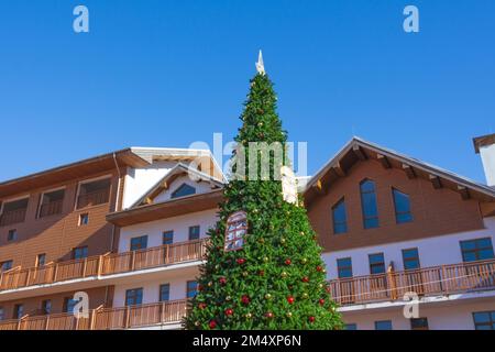 Arbre de Noël urbain décoré parmi les toits en pente de maisons en bois contre le ciel bleu Banque D'Images