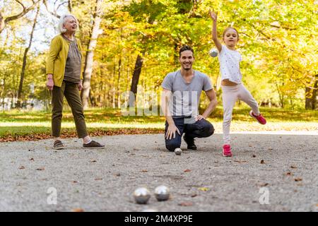 Femme âgée regardant une fille jouer aux boules avec son père dans le parc Banque D'Images