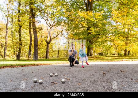 Fille jouant aux boules avec le père dans le parc Banque D'Images