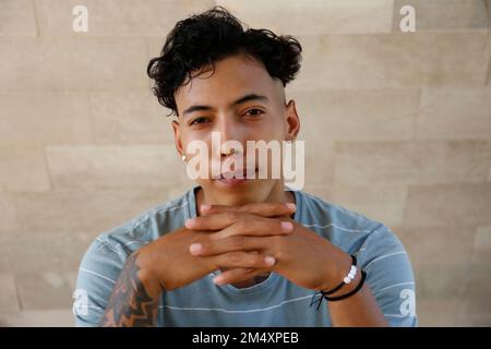 Jeune homme avec les mains clastées devant le mur Banque D'Images