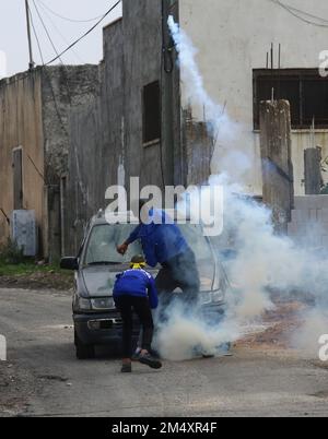 Naplouse, Palestine. 23rd décembre 2022. Un manifestant palestinien jette un bidon de gaz lacrymogène aux soldats israéliens lors d'affrontements à la suite d'une protestation contre l'expansion des colonies juives dans le village de Kufr Qadoom, en Cisjordanie, près de Naplouse, le 23 décembre 2022. Crédit: Nidal Eshtayeh/Xinhua/Alamy Live News Banque D'Images