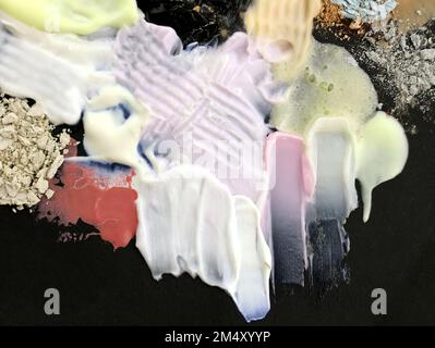 Gros plan sur des taches de crème, de rouge à lèvres et d'ombres. Composition abstraite de divers cosmétiques. Nuances de maquillage crème. Taches texturées, couché à plat Banque D'Images