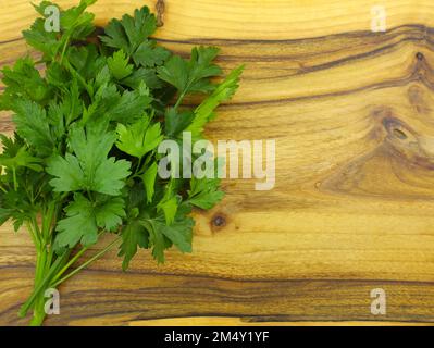 Un bouquet de persil frais sur une planche de cuisine. Vue de dessus des brins de persil. Herbes épicées pour la cuisine. bouquet de feuilles de persil vert sur une surface en bois Banque D'Images