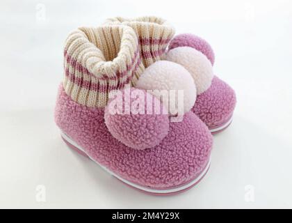 Chaussons en laine pour enfants avec balabon. Pantoufles chaudes roses pour filles. Une paire de chaussures pour enfant pour le froid sur fond blanc. Banque D'Images