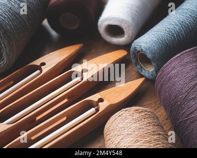 Trois navettes de bateau en bois avec fil dans des tons neutres, foyer sélectif. Préparation pour le tissage à la main Banque D'Images