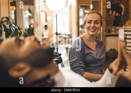 Couple heureux au salon de coiffure. Mariage hétérosexuel interracial visitant coiffeur et barbier ensemble. Un Indien flou au premier plan. Photo de haute qualité Banque D'Images