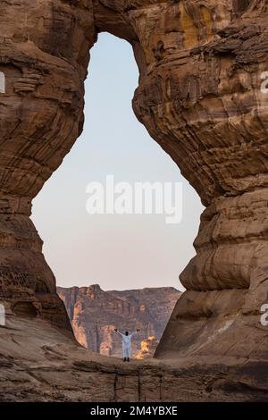 Homme debout dans un trou géant dans le rocher, Al Ula, Royaume d'Arabie Saoudite Banque D'Images