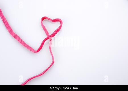 En forme de coeur fait par l'aide d'un sholace rose sur fond blanc Banque D'Images