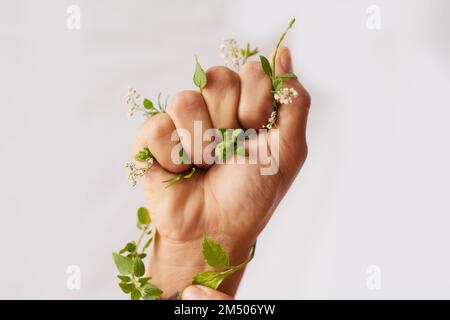 Prêtez une main à mère nature. une femme non identifiable qui accroche des fleurs dans un poing en studio. Banque D'Images