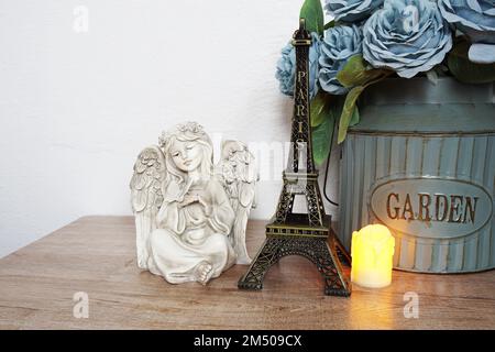 Étagères en bois décorées avec un souvenir de la tour Eiffel, une bougie LED et une petite statue d'ange Banque D'Images