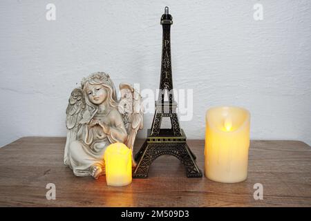 Étagères en bois décorées avec un souvenir de la tour Eiffel, une bougie LED et une petite statue d'ange Banque D'Images