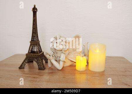 Étagères en bois décorées avec un souvenir de la tour Eiffel, une bougie LED et une petite statue d'ange Banque D'Images