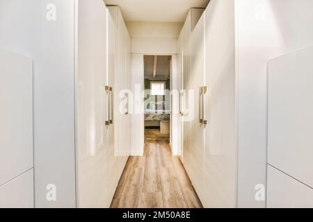 un long couloir étroit avec des murs blancs et du parquet la salle est bien éclairée par la lumière naturelle des fenêtres Banque D'Images