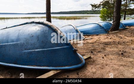 Des barques bleues se posent sur des talons sur une plage de sable Banque D'Images