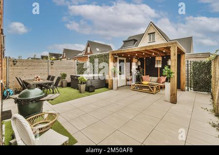 un salon extérieur avec des meubles de patio et des barbecues sur le côté de la maison, entouré d'herbe verte luxuriante Banque D'Images