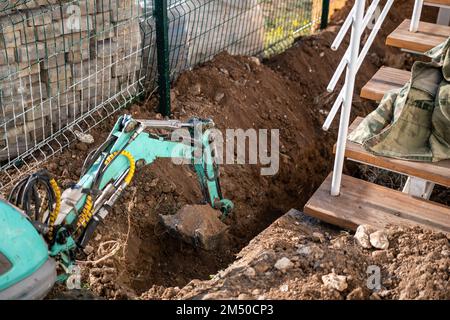 Une minipelle creuse une tranchée pour poser les tuyaux. Gros plan d'une pelle hydraulique creusant une tranchée profonde. Une pelle hydraulique creuse une tranchée dans la campagne pour déposer un Banque D'Images
