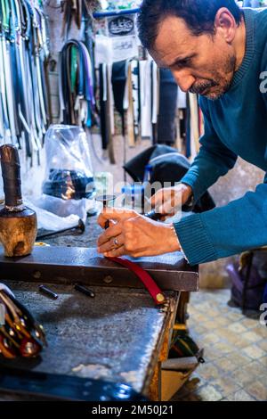 FES, Maroc; 7th décembre 2022: Un artisan du cuir travaille dans son atelier de la médina. Le cuir FES est connu pour sa qualité et sa douceur. Banque D'Images