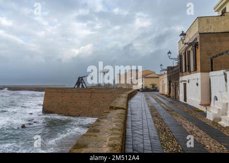 Alghero, Italie - 14 décembre 2022 : vue sur le front de mer historique avec murs fortifiés et défenses à Alghero sous un ciel couvert de tempête Banque D'Images