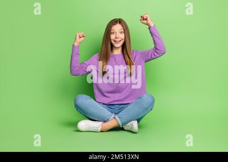 Pleine taille photo de belle positive impressionnée fille avec la longue coiffure vêtu jeans clenching poings isolés sur fond vert couleur Banque D'Images