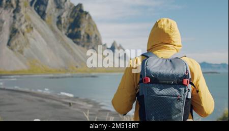 Homme voyageur à la recherche de montagnes fantastiques sur les dunes de sable de lave volcanique sur la plage Stokksness, Islande Banque D'Images