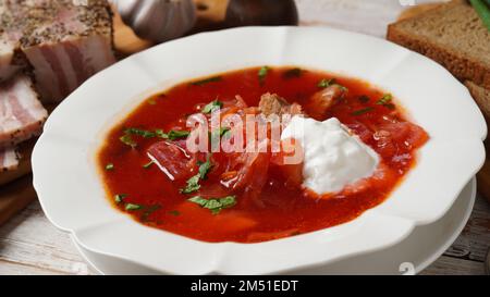 Borscht traditionnel ukrainien . Assiette blanche de soupe de racine de betterave rouge borsch à la crème blanche, oignon vert, filet de porc salé (salo). Déli Beet Root Banque D'Images