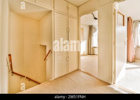 l'intérieur d'une pièce avec une porte ouverte et des vêtements suspendus sur des cintres devant les portes du placard Banque D'Images