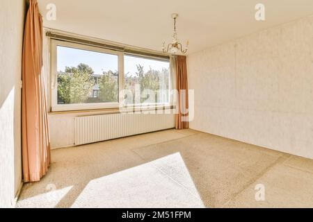 une chambre vide avec le soleil qui brille à travers la fenêtre et des rideaux suspendus sur la fenêtre qui se délitent devant la fenêtre Banque D'Images