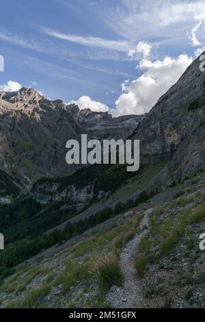 Cirque de Gavarnie avec chute d'eau à la formation massive de parois rocheuses et sentier de randonnée à travers la forêt dans les Pyrénées, Nouvelle-Aquitaine, France Banque D'Images