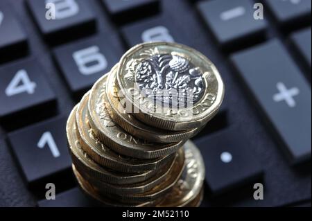 PILE DE PIÈCES D'UNE LIVRE SUR LA CALCULATRICE COÛT DE LA VIE CRISE PENSIONS INFLATION DES REVENUS BUDGETS DES MÉNAGES ETC ROYAUME-UNI Banque D'Images