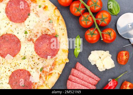 Pizza salami provenant d'ingrédients de cuisson ci-dessus gros plan sur une ardoise Banque D'Images