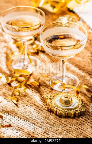 Deux verres de vin mousseux sur une table de fête pour le nouvel an, la fête ou le carnaval. Bouton-poussoir cloche pour champagne, dans un ton doré Banque D'Images