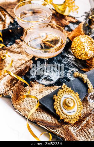 Deux verres de vin mousseux sur une table de fête pour le nouvel an, la fête ou le carnaval. Bouton-poussoir cloche pour champagne, dans un ton doré Banque D'Images