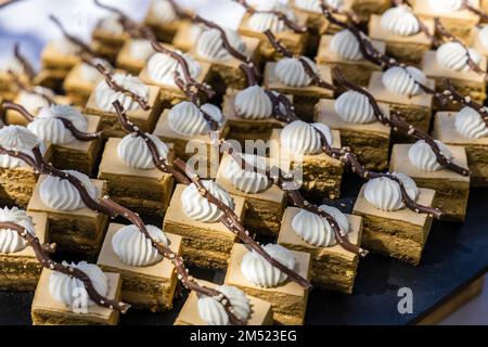 Un grand plateau de desserts sucrés raffinés est servi sous forme de buffet en plein air. Banque D'Images