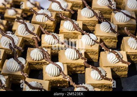 Un grand plateau de desserts sucrés raffinés est servi sous forme de buffet en plein air. Banque D'Images