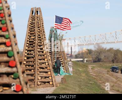 Gramercy, États-Unis. 23rd décembre 2022. Quelques jeunes retirent un peu de doublure en plastique d'un feu de camp tandis que le pont commémoratif des anciens combattants est en arrière-plan à Gramercy, Louisiane, vendredi, 23 décembre 2022. (Photo de Peter G. Forest/Sipa USA) crédit: SIPA USA/Alay Live News Banque D'Images