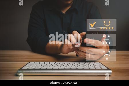 L'homme d'affaires attribue des notes à l'expérience de service sur un smartphone, aux évaluations et aux évaluations de satisfaction des fournisseurs de services, au concept de satisfaction et au client Banque D'Images