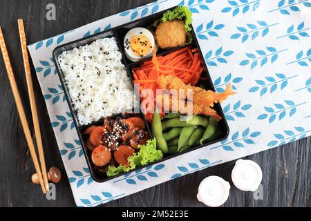 Top View Japanese Bento Box avec saucisse Teriyaki, carotte, œuf à la vapeur, Nugget, Edamame, Et crevettes Tempura Banque D'Images