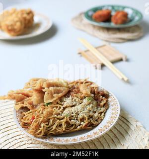 Mie Goreng ala Mie Gacoan, nouilles frite avec garniture de poulet déchiquetée. Servi avec des beignets. Nouilles frites épicées Banque D'Images