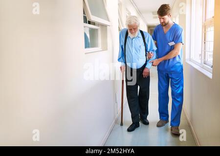 Marcher sur la route de la récupération ensemble. un jeune médecin aidant son patient âgé à marcher dans un couloir de l'hôpital. Banque D'Images