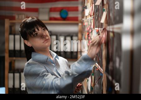 Jeune détective féminine regardant le tableau des preuves. Copier l'espace Banque D'Images