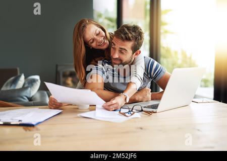 Nos investissements sont en grande forme. un jeune couple affectueux qui travaille sur le budget de son ménage. Banque D'Images