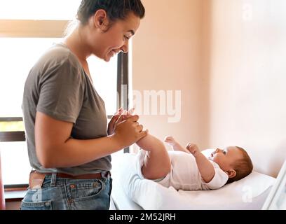 Bébé a-t-il besoin d'un changement de couche ? une jeune femme se liant à son bébé garçon à la maison. Banque D'Images