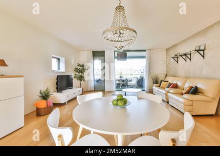 un salon avec parquet et mobilier blanc, dont une table ronde entourée de deux chaises blanches Banque D'Images