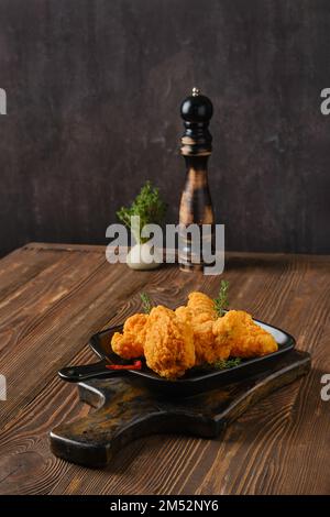 Ailes de poulet panées frites et épicées sur un plateau de service de sorbets Banque D'Images