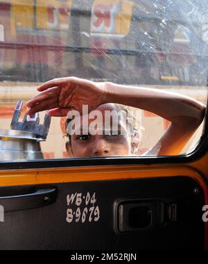 Un jeune mendiant frappe à la fenêtre et les taxis sur une rue animée de Kolkata. Banque D'Images